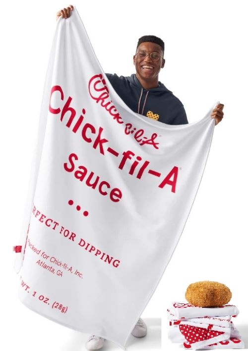 man holds up Chick-fil-A sauce blanket with inset of folded red and white blanket and chicken nugget pillow