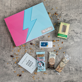 Recharge Kit with power bank and gourmet snacks, including a Taos Bakes bar, an Atlas protein bar by, a South Forty mixed nut bar and a pour-over coffee pack by Back Porch Coffee Roasters